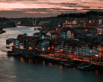 Aerial view of illuminated city buildings against sky at sunset