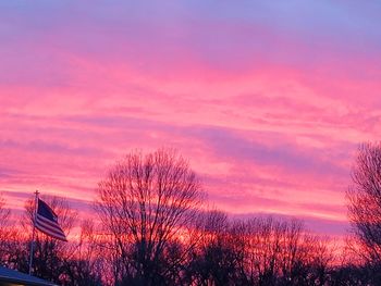 Silhouette bare trees and buildings against sky during sunset