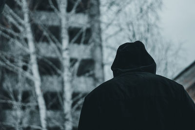 Rear view of man standing against trees during winter