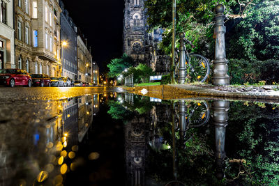 Reflection of illuminated building in puddle at night