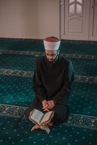 Man reading koran while sitting in mosque