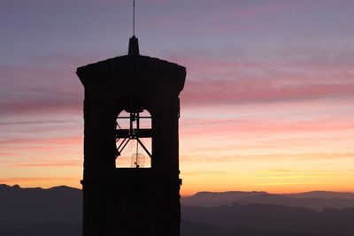 Silhouette built structure against orange sky