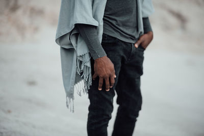 Midsection of man holding umbrella standing at shore