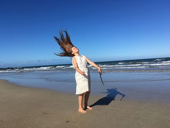 Full length of child standing on beach against clear blue sky