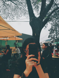 Reflection of woman photographing on mobile phone
