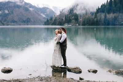 A loving married couple the bride and groom in suits celebrate wedding near the mountains and water