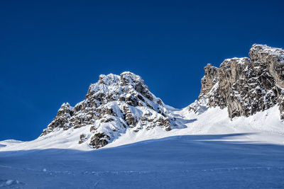 Scenic view of snowcapped mountains against clear blue sky