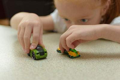 Close-up of girl playing with toy cars on table