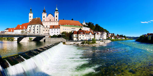 River amidst buildings against blue sky in steyr, upper austria