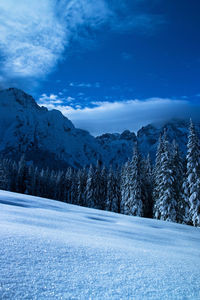 Scenic view of snow covered mountains against blue sky