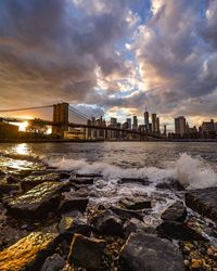 Sea by buildings against sky during sunset