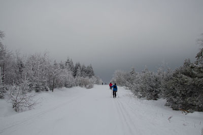 People on snowy field against sky during winter