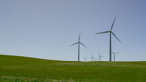 Windmills on field against clear sky
