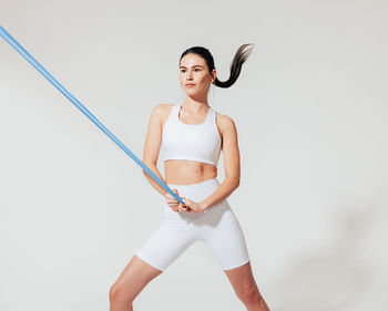 Portrait of young woman standing against white background