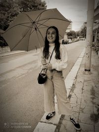 Portrait of young woman standing on street in rain