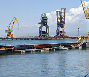 Cranes at pier against sky