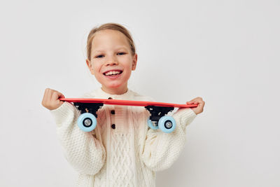 Portrait of cute girl holding toy against white background