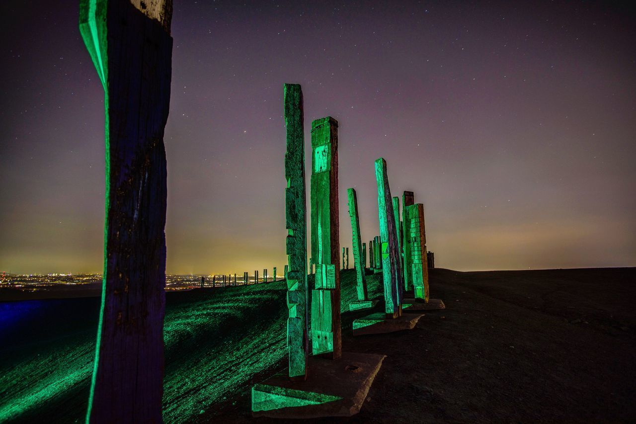 PANORAMIC VIEW OF WOODEN POSTS ON FIELD AGAINST SKY