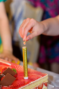 Closeup of a womans hand starting with a match a fountain firework on a cake