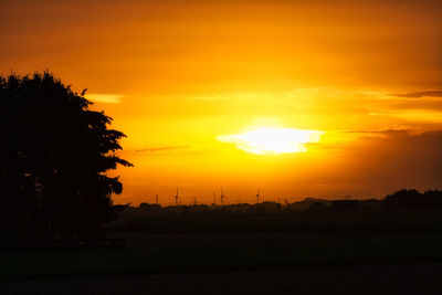 Silhouette trees on landscape against romantic sky at sunset