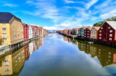 Buildings by river against sky