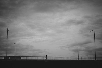 Low angle view of street lights against cloudy sky