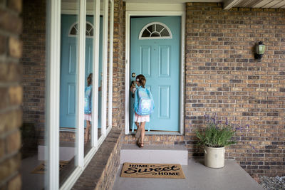 Girl with backpack opening door of house