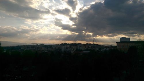 Cityscape against cloudy sky at sunset