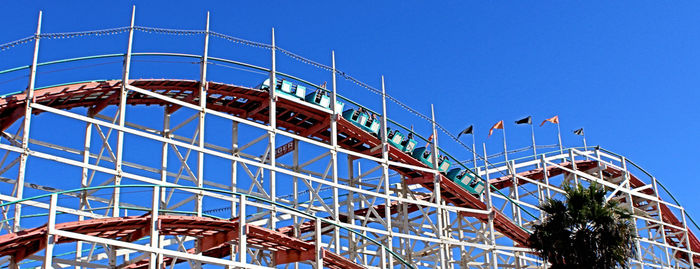 Low angle view of ferris wheel against clear blue sky