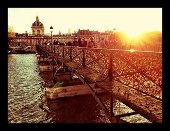 Sun shining over river in city