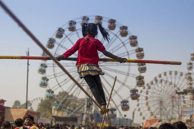 Rear view of people at amusement park against sky