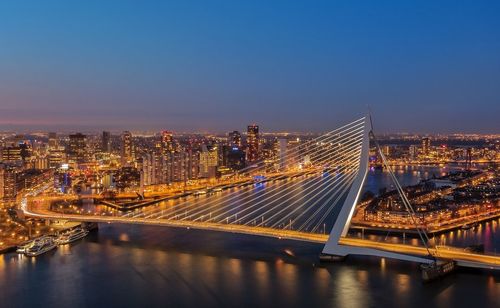 Illuminated bridge over river in city against sky at night