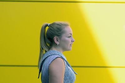 Woman looking away by yellow wall