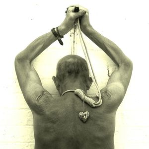 Rear view of shirtless man hanging against wall