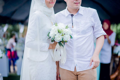 Midsection of couple holding flower