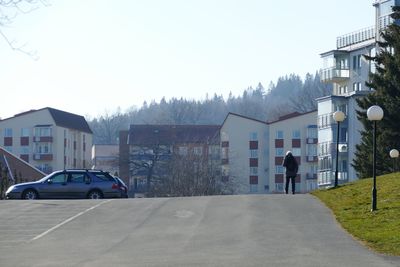 Cars on road by buildings against clear sky