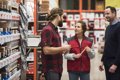 Saleswoman talking to male customers in hardware store