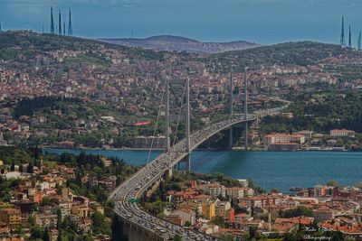 Bridge over river in city against sky