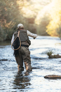 Rear view of fisherman fishing in river