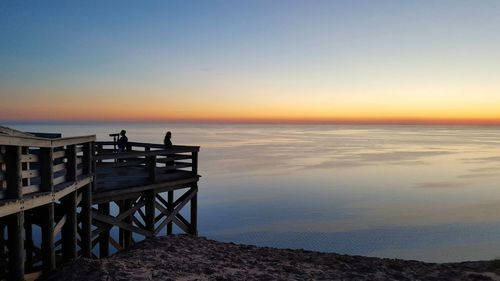 Pier by sea against sky during sunset