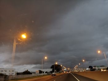 Cars on illuminated road against sky at night