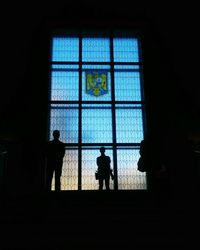 Silhouette people standing in window