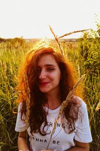 Portrait of smiling young woman standing on field against sky