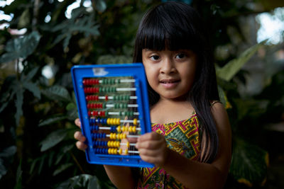 Close-up of girl playing with abacus against plants