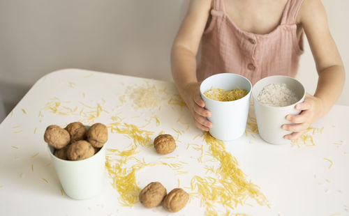 Baby hands playing with grain, nuts, pasta and rice at table.sensorial early development