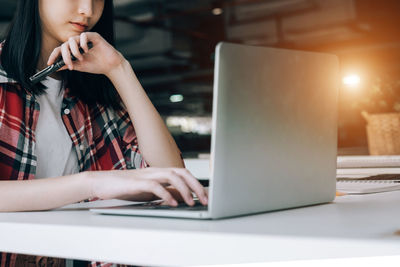 Midsection of woman using mobile phone while sitting on table