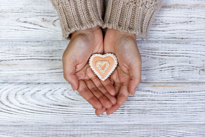 Directly above shot of copped hands holding heart shape cookie