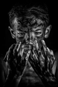 Close-up of dirty teenage boy against black background