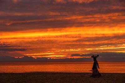 Silhouette man standing on beach against sky during sunset