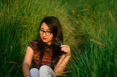 Beautiful young woman sitting on field
